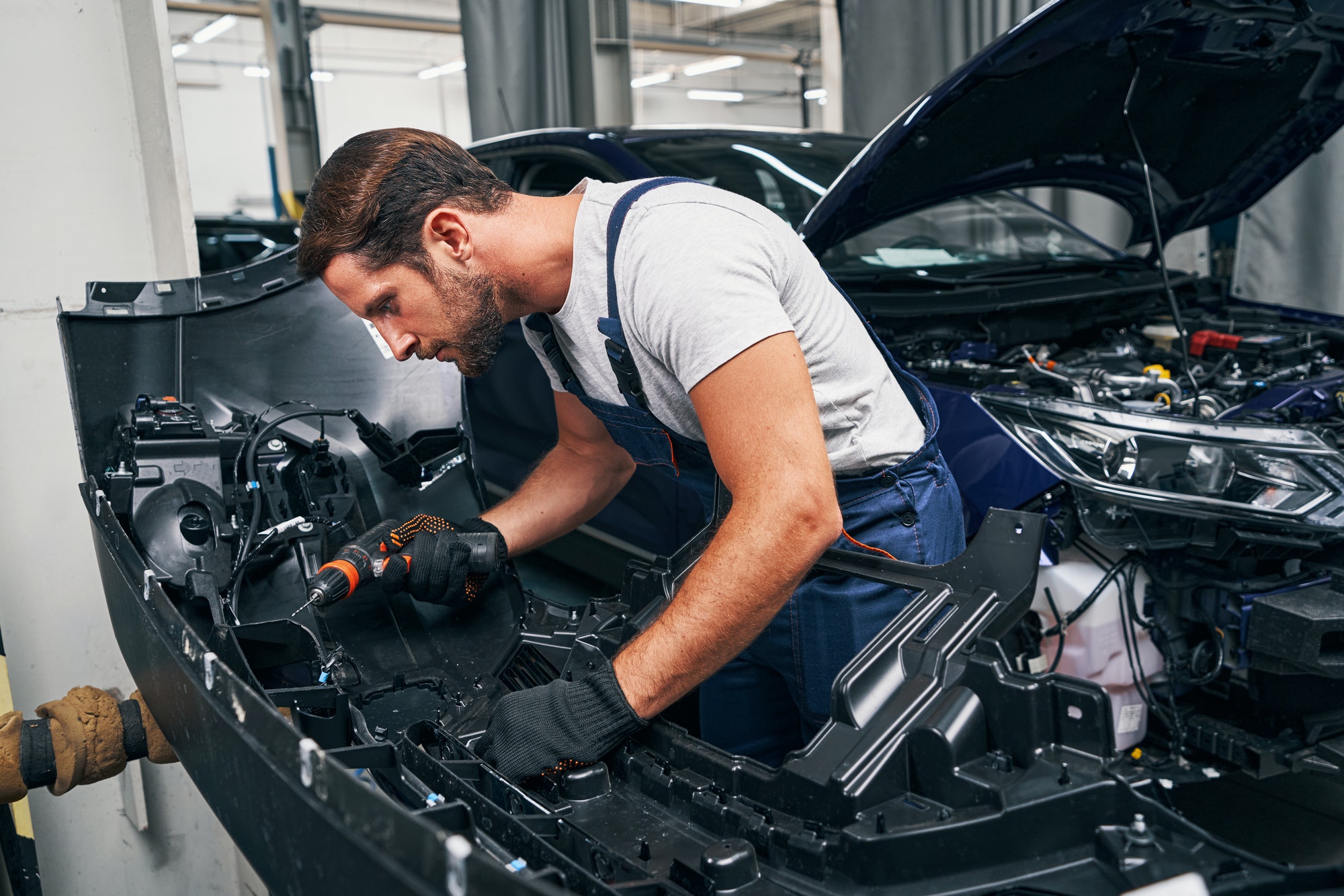 Automobile mechanic using drill on car part